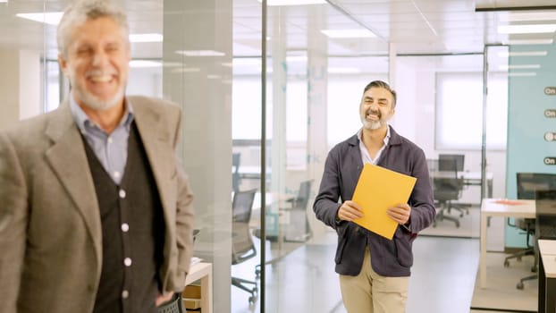 Two mature businessman smiling happily in a coworking office