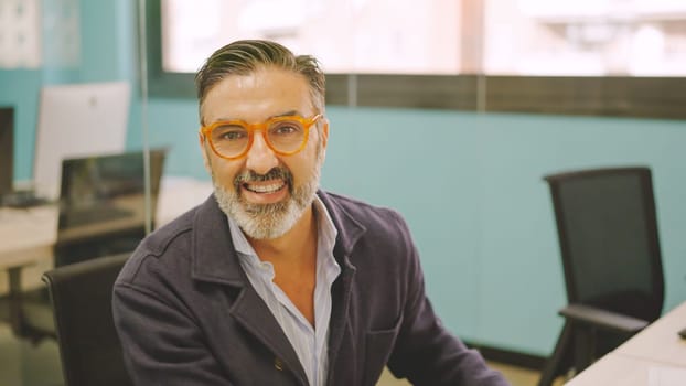 Mature man working in a coworking desk and smiling at camera