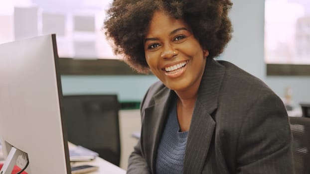 Female african american coworker smiling at camera sitting in the office