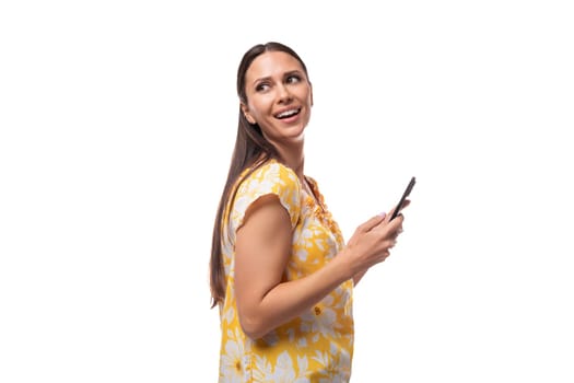 30 year old brunette woman dressed in a summer outfit chatting on a smartphone.