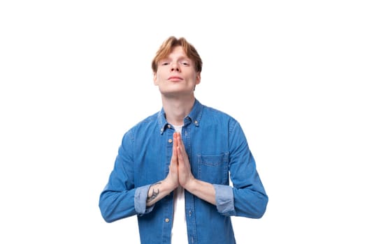 portrait of a calm handsome european red-haired student guy praying.
