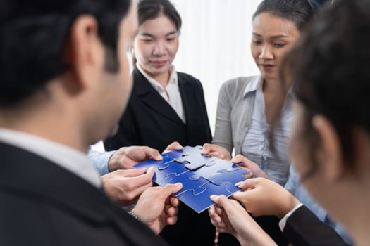 Multiethnic business people holding jigsaw pieces and merge them together as effective solution solving teamwork, shared vision and common goal combining diverse talent. Meticulous