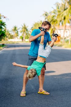 Father son have fun. Man holds child's leg upside down head. Joy happiness childhood paternity delight.