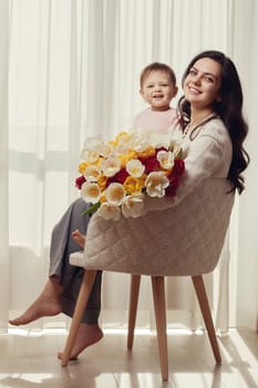 Cute little baby daughter and mom with flowers tulips. Mother and child hugging. Happy mother's day.