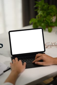 Closeup young businesswoman typing on keyboard, working with digital tablet at desk.