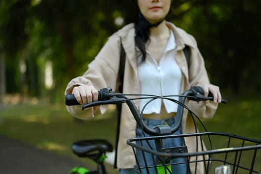 Young woman walking with bike in the public park. Eco friendly transport concept.