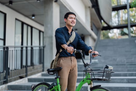 A man in a suit is riding a green bike with a basket. He is wearing a watch and a backpack