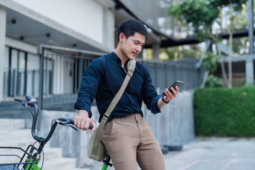 A man in a suit is standing next to a bicycle with a basket on it. He is looking at his cell phone