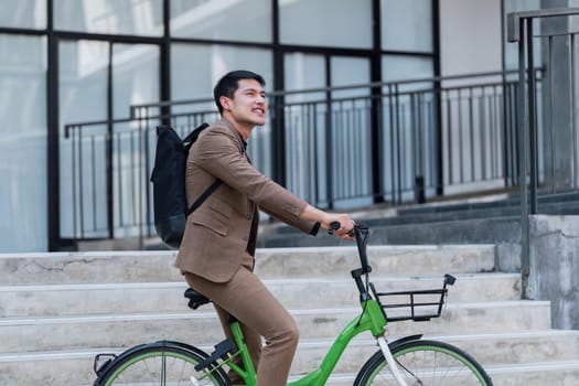 A man in a suit is riding a green bike with a basket. He is wearing a watch and a backpack