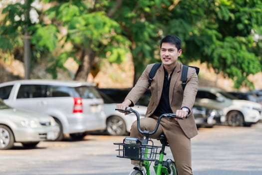 A man in a suit is riding a bicycle in front of a row of parked cars. Concept of urban life and the man's determination to get to his destination