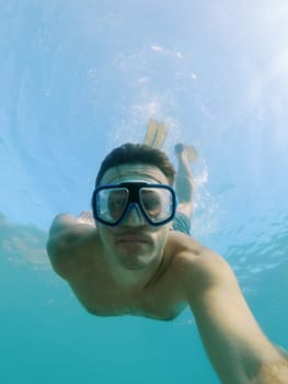 Diver in goggles and fins swims to a depth underwater. High quality photo