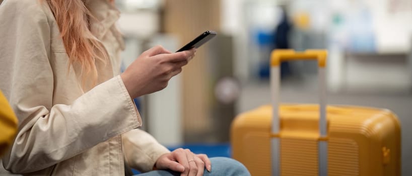 Tourist woman using mobile smartphone with suitcase traveling between waits for flight in Airport Terminal, flight check in, Tourist journey trip concept.