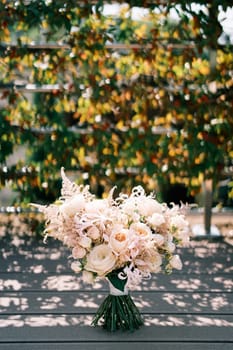 Bride bouquet stands on a wooden terrace in the garden. High quality photo
