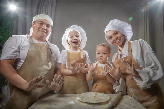 Cute oriental family with mother, father, daughter, son cooking in kitchen on Ramadan, Kurban-Bairam, Eid al-Adha. Funny family at a cook photo shoot. Pancakes, pastries, Maslenitsa, Easter