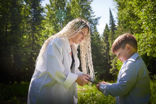 Young fat teenage boy playing with phone and mother swears, demands to stop it in a park. Blogger, gamer, streamer son online on Internet and conflict