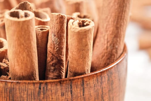 Small wooden bowl / cup with cinnamon bark sticks - closeup detail photo