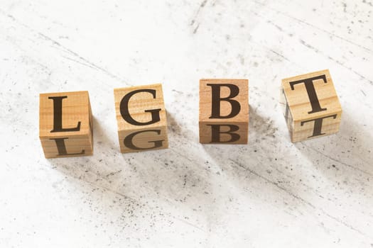 Four wooden cubes with letters LGBT (meaning lesbian, gay, bisexual, and transgender) on white working board.