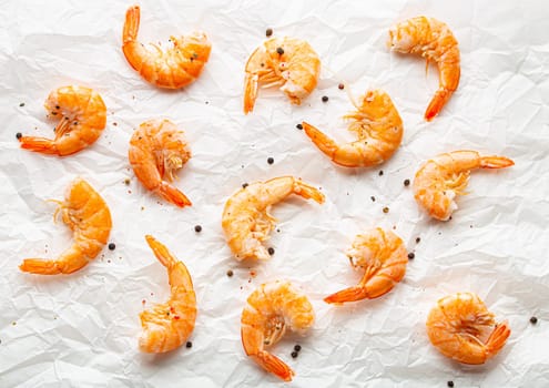 Roasted or grilled shrimps with seasonings top view on baking paper, healthy snack or appetizer. Seafood barbecue, food ingredient for salads.