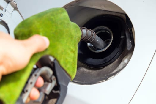 Close up image of hand refilling a car with fuel at a gas station, green fuel nozzle,energy concept