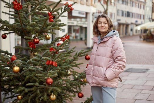 Elegance in the Old Town: Beautiful Woman Posing amidst the Festive Streets of Bietigheim-Bissingen, Germany . A beautiful girl stands on the street of the old European town of Bietigheim-Bissingen in Germany on Christmas Eve. City streets are decorated with Christmas trees and New Year's decorations, tourism, fashion, historical places, Europe