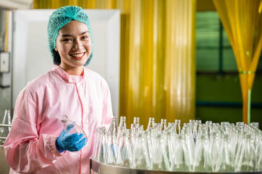 At a beverage factory industry a QC woman a worker in chemical science checks glass bottles quality for juice drinks maintaining meticulous industry standards.