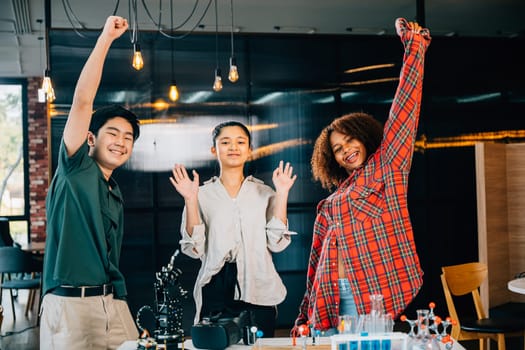 In classroom group of happy students learning about futuristic robotic arm technology joyfully raise hands to celebrate success after their engaging robotics class on Innovation and Technology.