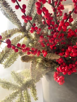 a bouquet of branches with red berries and fir branches in smoke in sunny weather, the rays of the sun through the branches. High quality photo