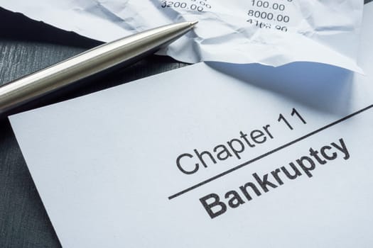 Chapter 11 bankruptcy and crumpled papers with financial statement.
