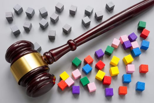 Wooden gavel separates gray cubes from colored ones. Legislation on equality and diversity. Social justice.