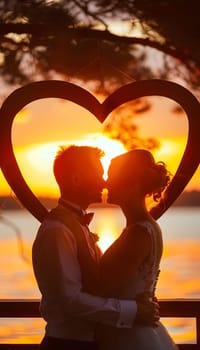 A happy couple kissing in front of a heartshaped frame at sunset, captured by flash photography in the warm sunlight. The scene is filled with love, joy, and beautiful tints and shades