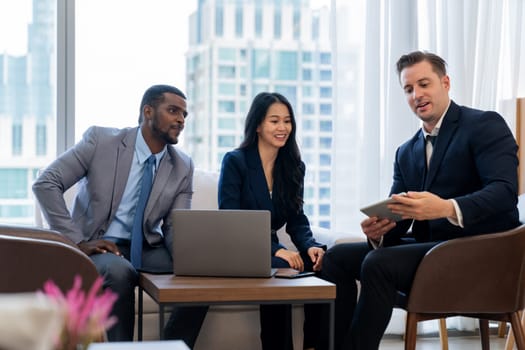 Smart caucasian businessman present marketing idea by using tablet. Group of business team listening while deciding to invest in start up project at modern lounge. Ornamented.