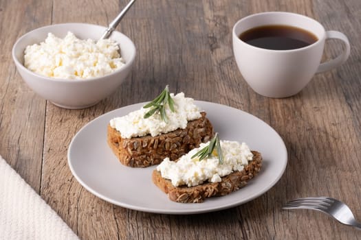 Homemade rye bread with cottage cheese in a plate and coffee. Healthy breakfast concept.