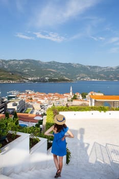 A girl in a blue dress admires a picturesque coastal town that captures the combination of natural beauty and architectural charm. Montenegro