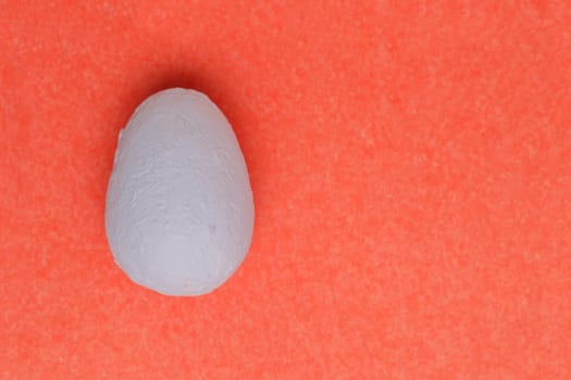 Close-up macro flatlay, with texture. Decorative hand painted light blue egg on a pink paper background.