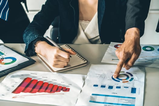 Businessman and businesswoman in meeting working with many financial statement document on desk. Concept of busy business profit analysis and brainstorm. Close up shot at people hands and papers. uds