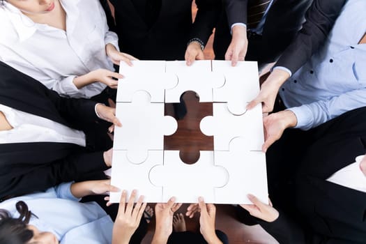 Top view multiethnic business people holding jigsaw pieces and merge them together as effective solution solving teamwork, shared vision and common goal combining diverse talent. Meticulous