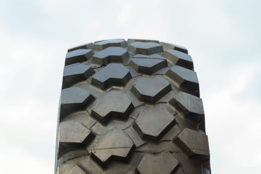 Detailed view of a tire with treads visible, set against a clear blue sky background.