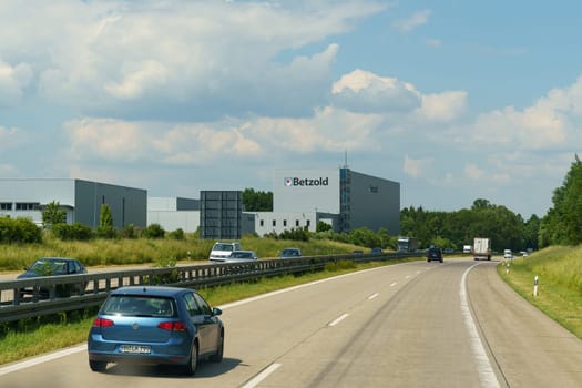 Gunn. Munden, Germany - June 9, 2023: Vehicles traveling on a highway under clear skies, with a large Betzold sign visible on an adjacent building.