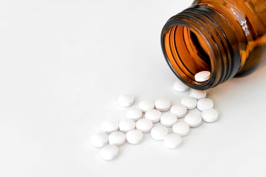 Medication Close-Up: White Pills and Brown Glass Vial Arranged on Table, Copy Space, Close-Up, Healthcare Concept..