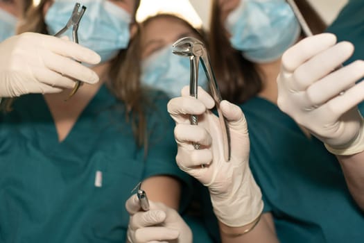 Hands of dentists surgeons with forceps and instruments for dental treatment