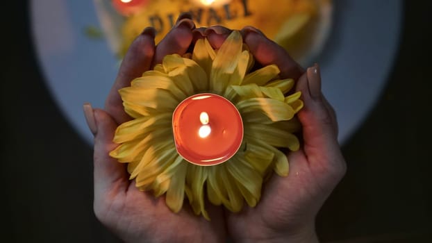 Celebration of the religious Indian festival of Diwali. Yellow flowers with burning holi candles at Hindi festival close-up