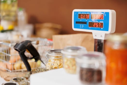 Close up shot of eco friendly checkout counter displaying weighing scale, barcode scanner, and variety of fresh sustainable products in glass containers.