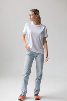 Beautiful blonde woman in a white T-shirt and blue jeans posing on a white background. High quality photo