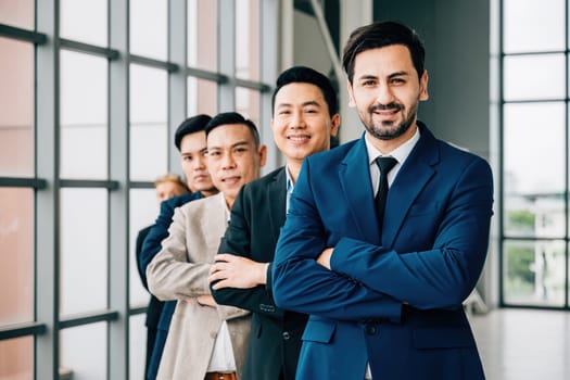 Young businesspeople and a businessman gather indoors, standing with crossed arms in the office. Their unity, success, and teamwork shine in this dynamic group portrait.