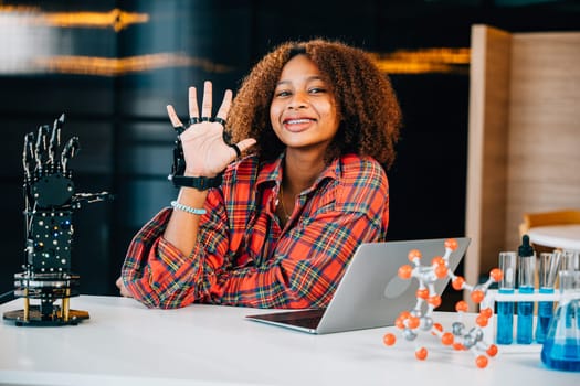 Black teenage student in a classroom learns and tests a robotic arm on a table delving into subjects of interest. Embracing innovation and technology for skill development in education.