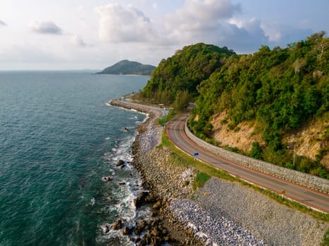 car driving on the curved road alongside the ocean beach road of Thailand. road landscape in summer. it's nice to drive on the beachside highway. Chantaburi Province Thailand, drone aerial view