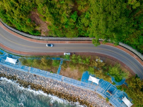 car driving on the curved road alongside the ocean beach road. road landscape in summer. it's nice to drive on the beachside highway. Chantaburi Province Thailand, top view drone