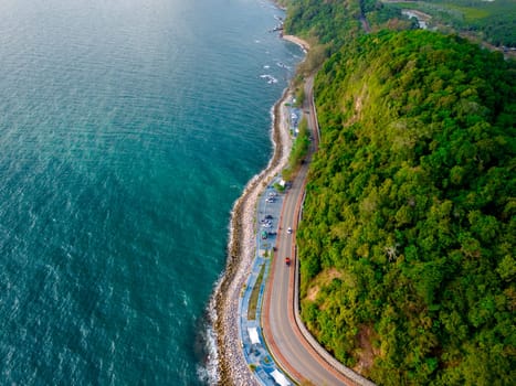 car driving on the curved road alongside the ocean beach road in summer. it's nice to drive on the beachside highway. Chantaburi Province Thailand, top drone view