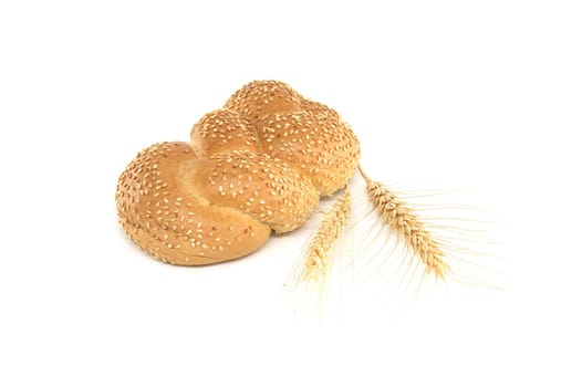 Braided sesame bun and a stalks of wheat isolated on white background