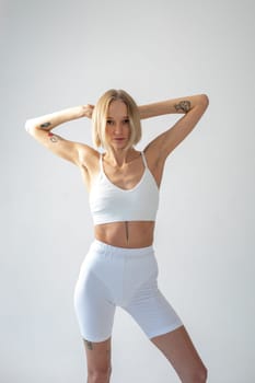 Blonde girl posing on a white background in a top and leggings. High quality photo